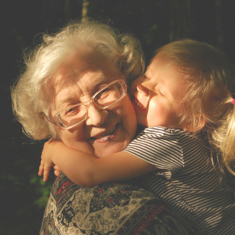 Femme âgée souriante avec une petite fille l'embrassant tendrement.